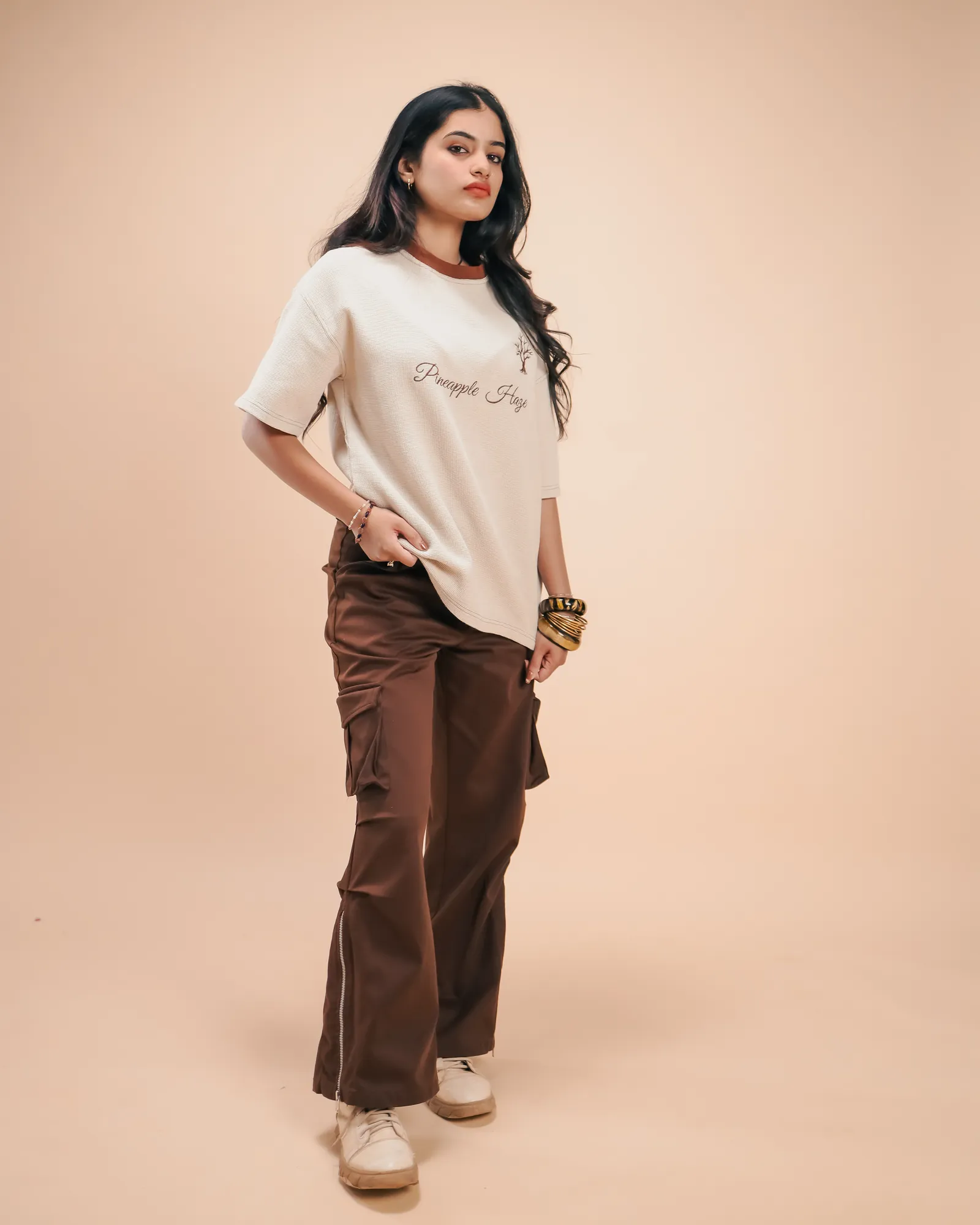Full length in the Pineapple Haze tee, one hand at the hem